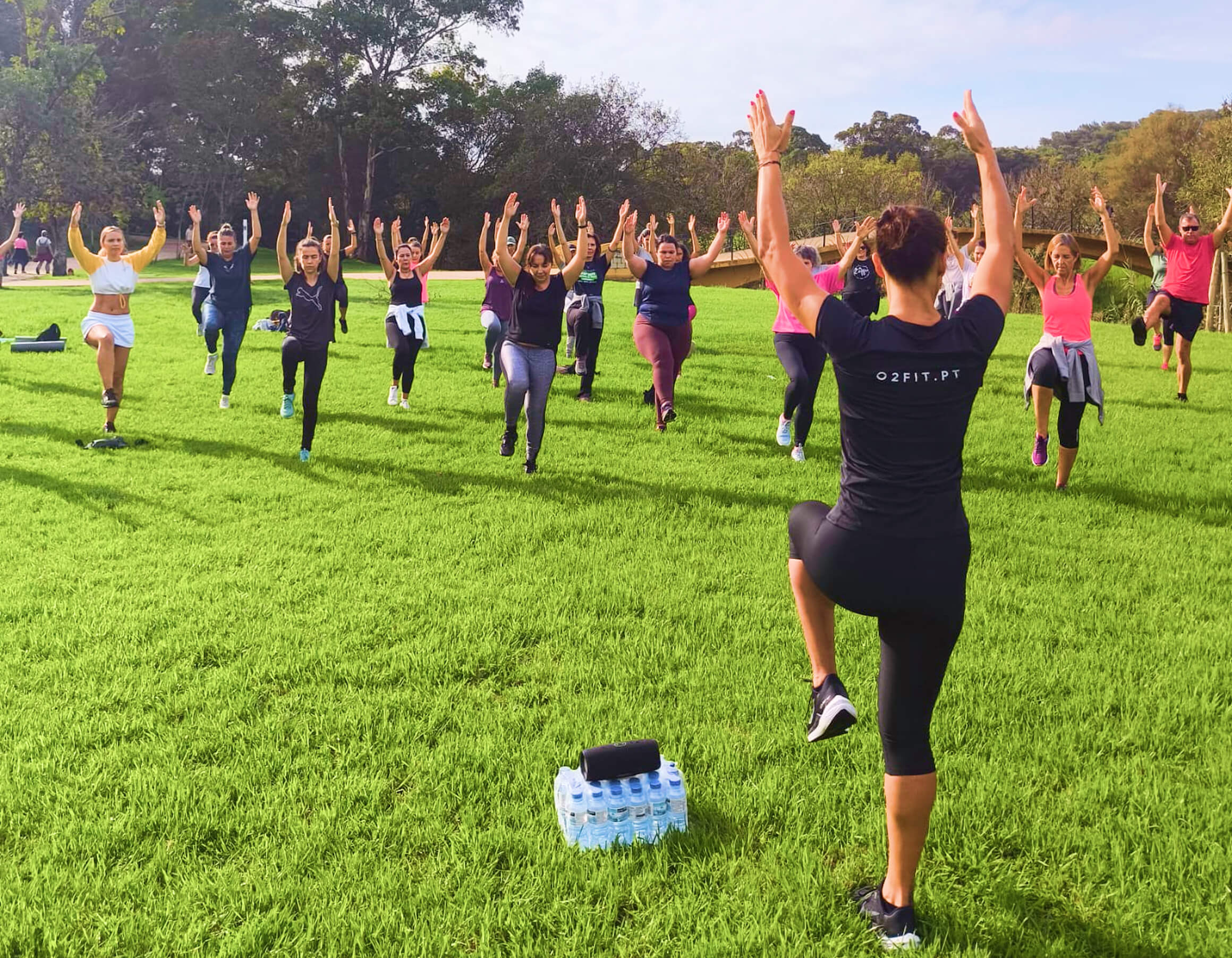 Alunas e alunos O2Fit de braços no ar junto a um lago
